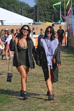 two women walking in the grass at an outdoor event