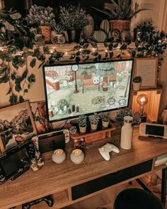 a desk with a computer monitor and various plants on it, along with other items