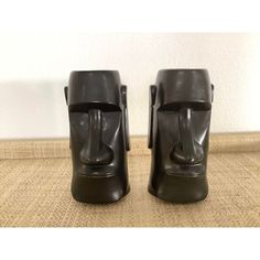 pair of black ceramic head vases on brown carpeted floor with white wall in background