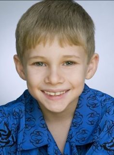 a young boy wearing a blue shirt and smiling