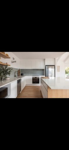 an empty kitchen with white cabinets and wood flooring