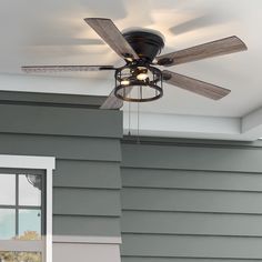 a ceiling fan that is on the outside of a house in front of a window