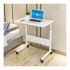 a laptop computer sitting on top of a white desk next to a wooden bed frame