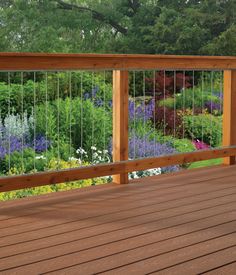 a wooden deck with metal railing and flowers in the background