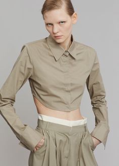 Color: Olive Crisp cotton poplin Fitted silhouette Highly cropped profile Padded shoulders Pointed collar Button front closure Curved hem 100% Cotton Dry Clean By The Frankie Shop. Imported Product Measurements: XS- 15.5" Shoulder, 34" Bust, 13.5" Length S- 16" Shoulder, 36" Bust, 14" Length M- 16.5" Shoulder, 38" Bust, 14.5" Length L- 17" Shoulder, 40" Bust, 15" Length Model is 178cm/ 5'10" wearing size S Chic Fitted Cropped Shirt With Collar, Chic Cropped Cotton Shirt, Chic Collared Cotton Crop Top, Fitted Collared Cotton Crop Top, Fitted Cotton Cropped Shirt For Work, Fitted Cotton Collared Crop Top, Fitted Cropped Shirt With Button Closure, Fitted Cropped Cotton Shirt, Chic Cotton Cropped Shirt With Buttons