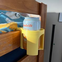 there is a cup holder on the side of a bed with a drink in it