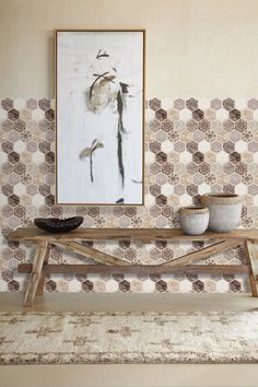 a wooden bench sitting in front of a painting on a wall next to a rug