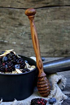 a wooden spoon sitting next to a bowl filled with berries