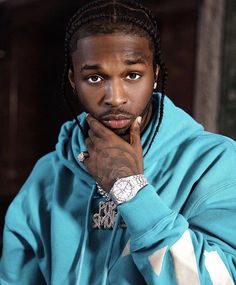 a man with dreadlocks wearing a blue hoodie and looking at the camera