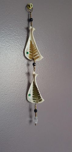 two bells hanging from the side of a wall with glass beads on each earring