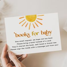 a person holding up a card with the words book for baby written in orange and yellow