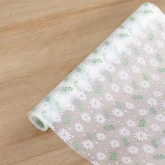 a white and green flowered fabric on a wooden surface