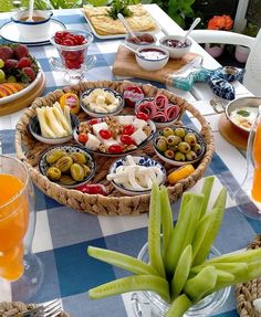 a table with plates and bowls of food on it, including grapes, olives, tomatoes, bread