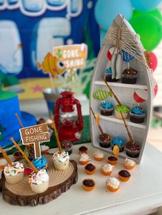 there are cupcakes on the table with fishing signs and other decorations around it