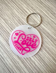 a pink heart shaped keychain with the words self love and peace on it