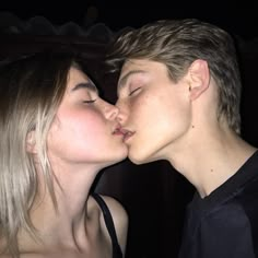 two people are kissing each other with their noses close to one another while the woman is wearing a black shirt