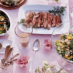 a table topped with plates and bowls filled with food next to salads, drinks and utensils