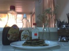 a plate with some pancakes on it next to bottles and utensils in the kitchen