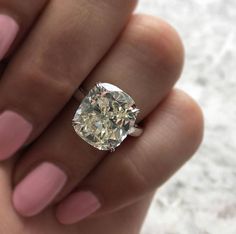 a close up of a person holding a ring with a large diamond in the middle