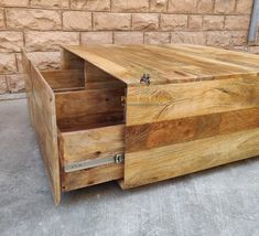 a large wooden box sitting on top of a cement floor next to a brick wall