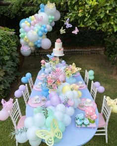 a blue table topped with lots of balloons next to a cake and cupcakes