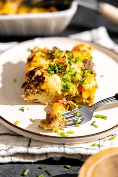 a white plate topped with a slice of casserole and a fork next to it