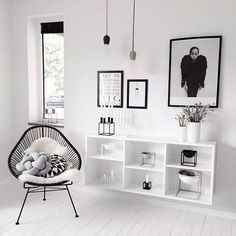 a white room with black and white pictures on the wall, a hanging chair in front of a book shelf