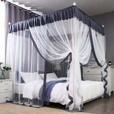 a white and blue canopy bed sitting next to a night stand with two nightstands