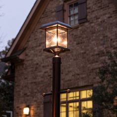 a lamp post in front of a house at night with the light on it's side