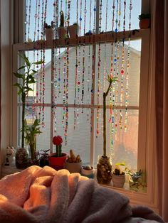 a window with beads hanging from it's side and a blanket on the windowsill