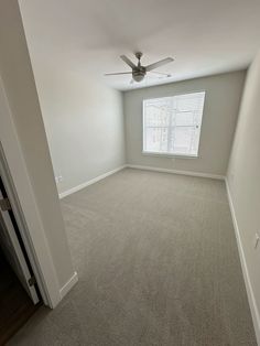 an empty room with carpet and ceiling fan