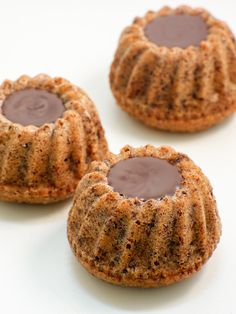 three cookies with chocolate filling sitting on a white surface