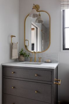 a bathroom with a sink, mirror and gold faucet on the vanity top