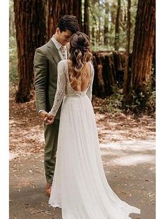 a bride and groom are standing in the woods holding hands, looking at each other