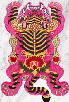 a pink and yellow rug with an animal design on it's back side, in front of a white marble background