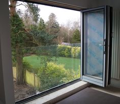 an open window looking out onto a green yard and trees in the backround