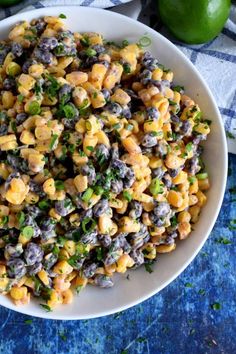 a white bowl filled with corn salad on top of a blue and white checkered table cloth