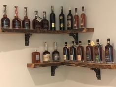 several bottles of liquor are lined up on wooden shelves in a room with white walls