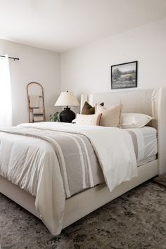 a bed with white sheets and pillows in a bedroom