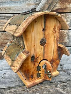 a bird house made out of wood on the side of a wooden building with an open door