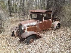 an old rusted out truck sitting in the woods