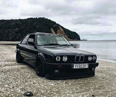 a black car parked on top of a sandy beach