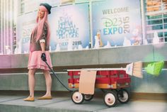 a woman is cleaning the steps with a red wagon and green duster on wheels