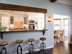 an open kitchen and living room with bar stools