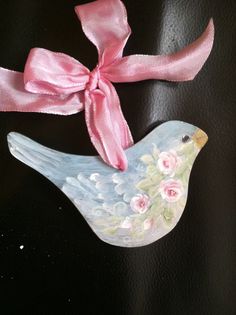 a pink ribbon tied around a bird with flowers on it's head and neck