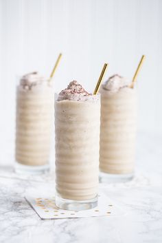 two glasses filled with ice cream on top of a white table next to each other