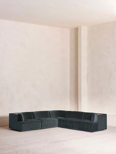 a black couch sitting on top of a hard wood floor next to a white wall