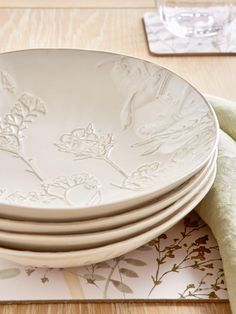 a stack of white plates sitting on top of a wooden table next to a napkin