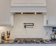 a stove top oven sitting inside of a kitchen next to white cabinets and counter tops