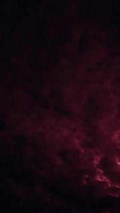 an airplane is flying in the sky at night with red and purple clouds behind it